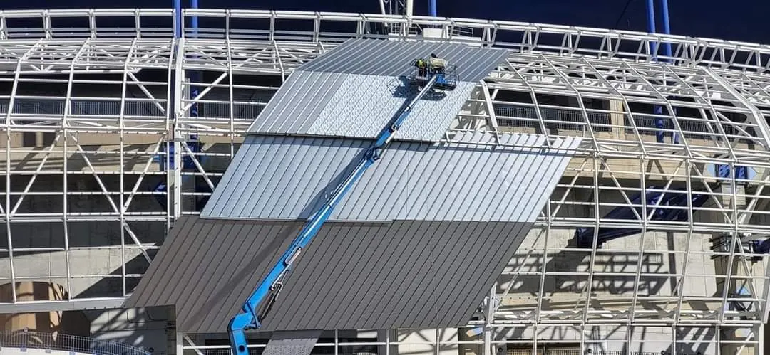 Nacelle télescopique bleue pour pose de bardage sur façade de stade au Maroc